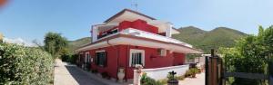 a red and white house with mountains in the background at Valeri 's Country House in Sperlonga