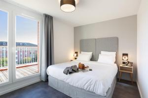 a bedroom with a bed and a large window at Appart Hotel Odalys City Toulouse Centre Compans Caffarelli in Toulouse