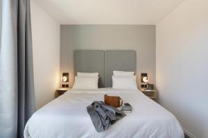 a bedroom with a large white bed with a bag on it at Appart Hotel Odalys City Toulouse Centre Compans Caffarelli in Toulouse