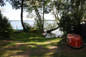 a red boat sitting on the grass near the water at Ferienhof Löschebrand in Bad Saarow