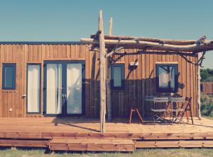 a wooden cabin with a porch and a table on a deck at Camping Les Bois Flottés in Salin-de-Giraud