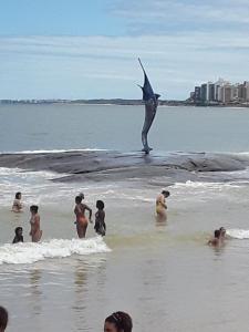 un grupo de personas en la playa con un tiburón en el agua en Apartamento na Praia do Morro, en Guarapari