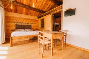 a bedroom with a bed and a wooden table and chairs at L'Escola e Lou Mulin in Sampeire