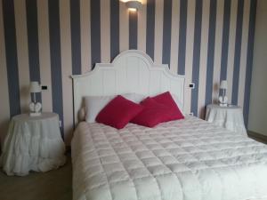 um quarto com uma cama branca e almofadas vermelhas em Agriturismo Fioredizucca em Albenga