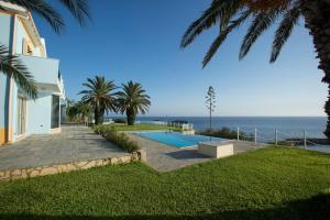 a house with a swimming pool next to the ocean at Ionian Blue Luxury Villas in Svoronata