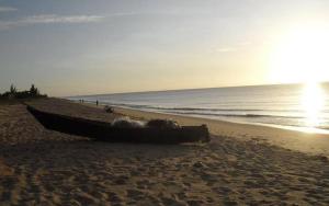 um barco sentado numa praia perto do oceano em Casa frente para o mar em Nova Viçosa