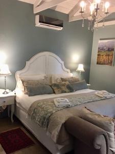 um quarto com uma grande cama branca e um lustre em Morgenzon Estate em Pretoria
