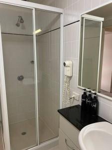 La salle de bains est pourvue d'une douche et d'un lavabo. dans l'établissement RIVERSIDE CITY VIEW PARKING NETFLIX WIFI WINE FREE, à Perth