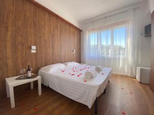 a bedroom with a bed with red rose petals on it at Borghetto Hotel in Santa Marinella