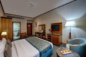 a hotel room with a bed and a desk and a television at Orchid Hotel Al Barsha "Formerly Golden Tulip Hotel Al Barsha" in Dubai