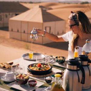 Berber Soul luxury Camp في مرزوقة: تقوم المرأة بإعداد وجبة على طاولة