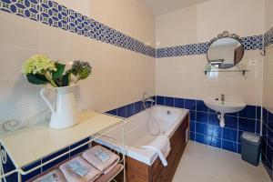 Penzión Starý Hostinec في بانسكا شتيفنيتسا: حمام باللون الأزرق والأبيض مع حوض استحمام ومغسلة