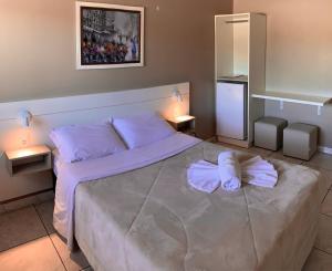 a bedroom with a bed with two white shoes on it at Pousada Bello Outono in Canela