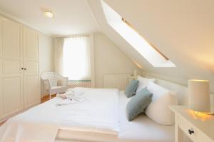 a white bedroom with a white bed with blue pillows at Ferienhaus für 8 Personen mit Kamin & Terrasse in Boltenhagen