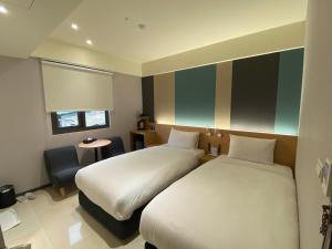 ein Hotelzimmer mit 2 Betten und einem Stuhl in der Unterkunft Fu Kuang Hotel in Pingtung