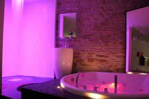 La salle de bains est pourvue d'une baignoire avec des lumières roses. dans l'établissement Le Lovt - LOVE ROOM NANTES, à Nantes