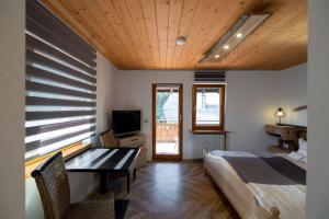 una camera con letto, scrivania e TV di Berghotel und Restaurant Kräuter Chalet a Furtwangen