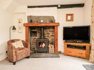 a living room with a fireplace and a tv at Beckfold Cottage in Broughton in Furness