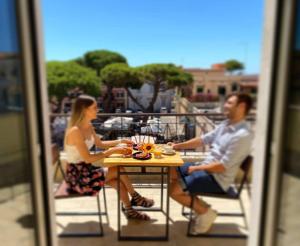 a man and woman sitting at a table on a balcony at Borghetto Hotel in Santa Marinella