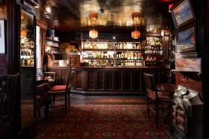バセンスウェイトにあるThe Pheasant Inn - The Inn Collection Groupの椅子のあるバーとアルコールのあるバーカウンター