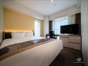 a hotel room with a bed and a flat screen tv at Daiwa Roynet Hotel Kumamoto in Kumamoto