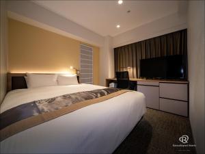 um quarto de hotel com uma cama grande e uma televisão de ecrã plano em Daiwa Roynet Hotel Kumamoto em Kumamoto