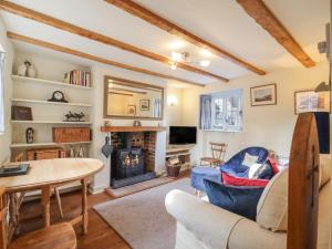 a living room with a fireplace and a table at Wayside Cottage in Bedford