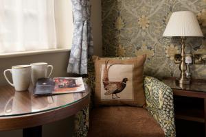 Cette chambre comprend une table et une chaise avec un oreiller. dans l'établissement The Pheasant Inn - The Inn Collection Group, à Bassenthwaite