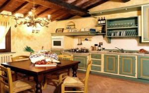 una cucina con armadi verdi e tavolo in legno di Villa Vignola a Montaione