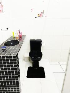 a bathroom with a black toilet and a sink at Aeroporto House 4 in Macapá