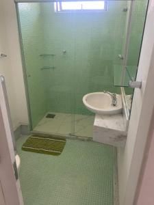 uma casa de banho com um lavatório e uma cabina de duche em vidro. em Apartamento Inteiro com Vista do Lago Quitandinha em Petrópolis