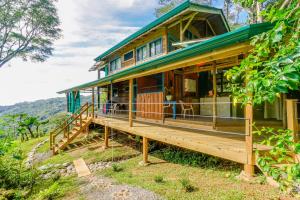 ein Haus auf einem Hügel mit einer großen Veranda in der Unterkunft Edge of the World in Dominical