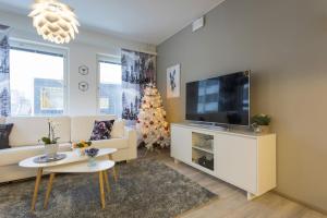 un salon avec une télévision et un arbre de Noël dans l'établissement Tuomas´ luxurious suites, Livo, à Rovaniemi