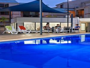 a swimming pool with a patio area with chairs and umbrellas at Mont Clare Boutique Apartments in Perth