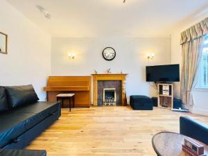 a living room with a piano and a clock on the wall at Millerston House in Glasgow