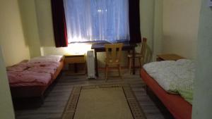 Zimmer mit 2 Betten, einem Schreibtisch und einem Tisch in der Unterkunft LINDENHOF WALDHEIM in Waldheim