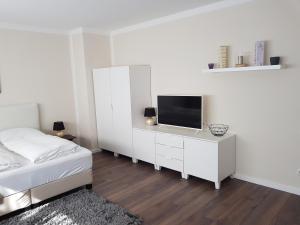 a white bedroom with a bed and a tv at City Apartments in Krefeld