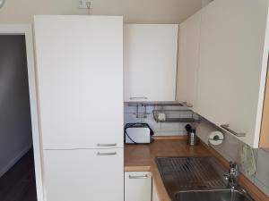 una cocina con armarios blancos y fregadero en City Apartments en Krefeld