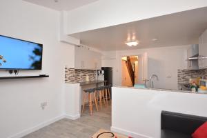 a kitchen and living room with a flat screen tv at Newly refurbished 3 bedroom house London in Woolwich