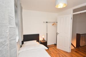 a bedroom with a bed with white sheets and a lamp at Newly refurbished 3 bedroom house London in Woolwich