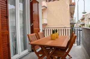een houten tafel en stoelen op een balkon bij Appartamento le calette in Stazzo