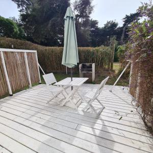 an umbrella and two chairs on a wooden deck at Villa Agostina Apart & Spa in Mar de las Pampas