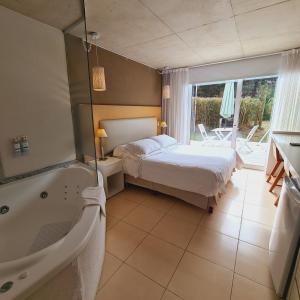 - une chambre avec un lit et une baignoire à côté d'une salle de bains dans l'établissement Villa Agostina Apart & Spa, à Mar de las Pampas