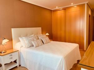 sypialnia z białym łóżkiem i drewnianą ścianą w obiekcie SANXENXO SUITES CON VISTAS Muy Bien Ubicado w mieście Sanxenxo