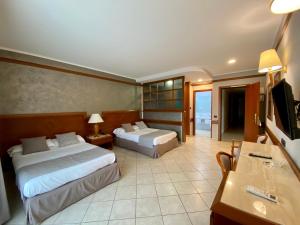 una camera d'albergo con due letti e una televisione di Hotel Le Palme a Paestum