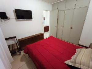 1 dormitorio con cama roja y TV en la pared en EF Departamentos Plaza Colon Con Cochera en Mar del Plata