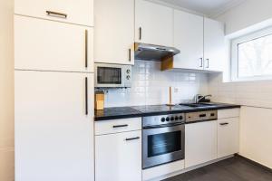 a kitchen with white cabinets and a stove top oven at Experience Central Vienna from a Stylish and Modern Apartment in Vienna