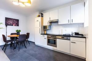 a kitchen with white cabinets and a table with chairs at Experience Central Vienna from a Stylish and Modern Apartment in Vienna