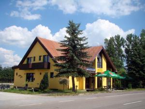żółty dom z drzewem przed nim w obiekcie Restaurace penzion Rafael w mieście Dlouhá Brtnice