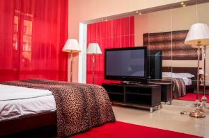 um quarto de hotel com televisão e cortinas vermelhas em Belvedere Nevsky Business Hotel em São Petersburgo